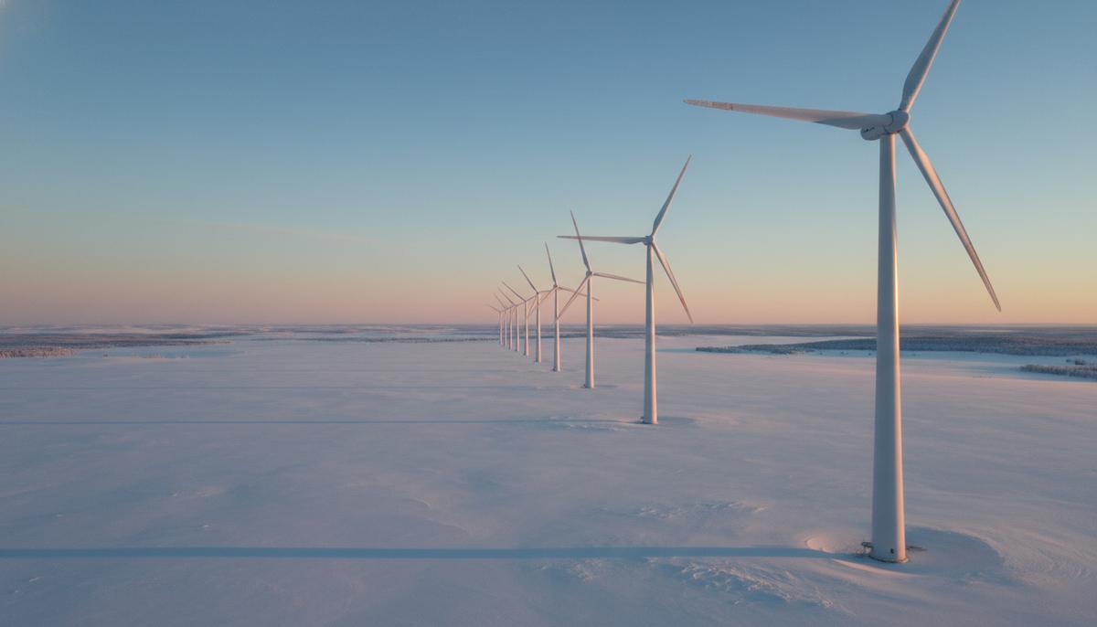 Современные ветряные турбины, установленные на заснеженном поле в зимний период. Холодный пейзаж с объектами возобновляемой энергетики.